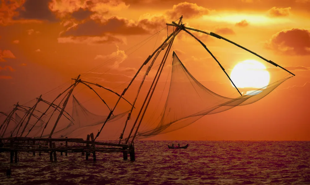 Sunset over Chinese Fishing nets and boat in Cochin (Kochi), Kerala, India.