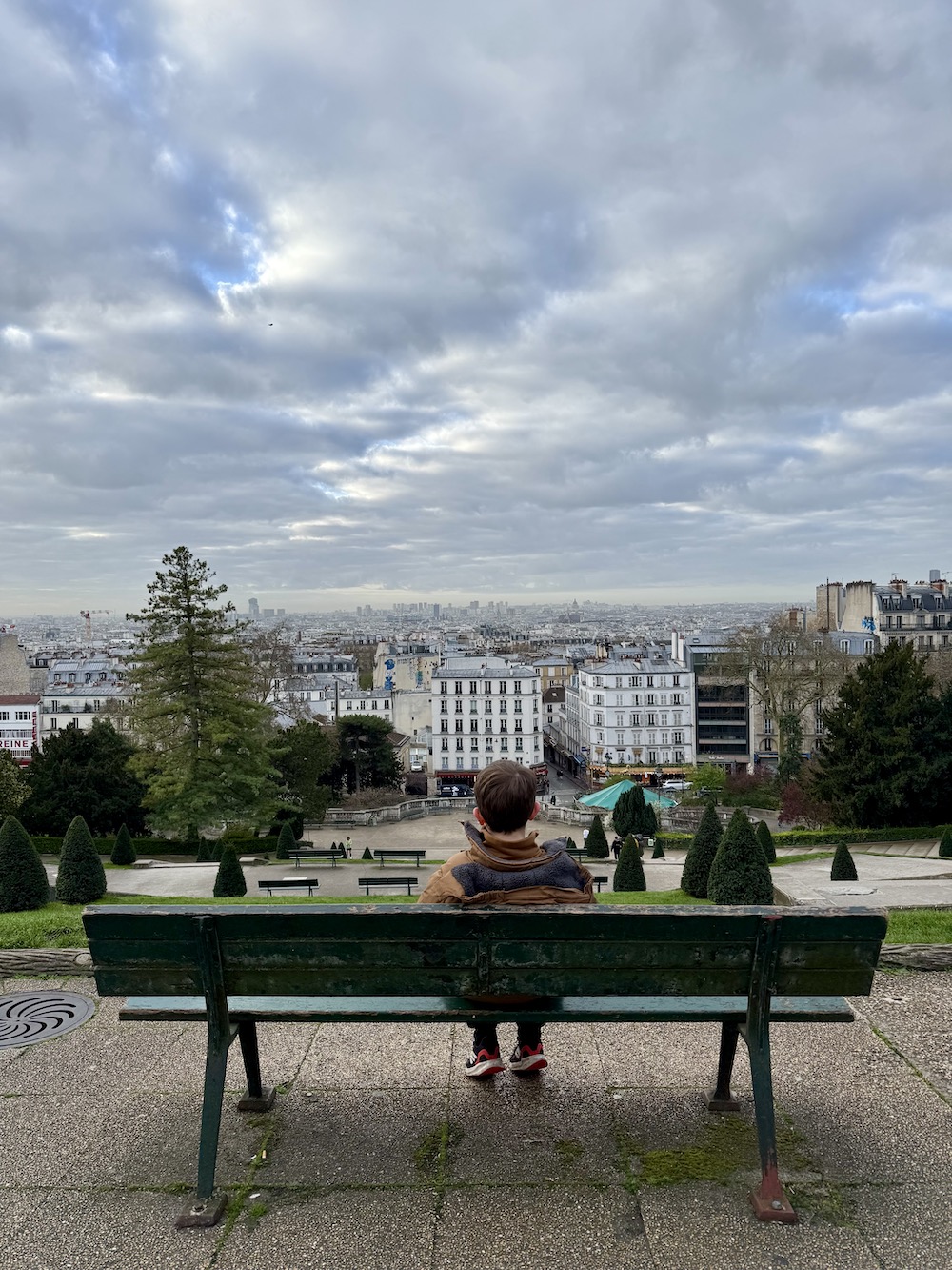Boy overlooking Paris from a bench at Sacre Coeur