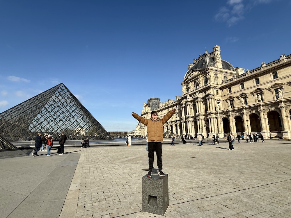 Boy at the Lourve in Paris standing on a block