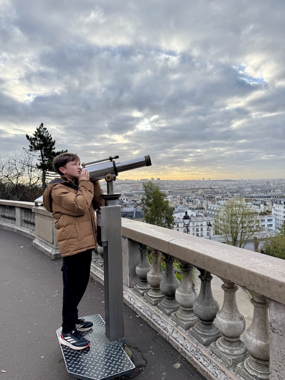 Boy looking over Paris through a telescope